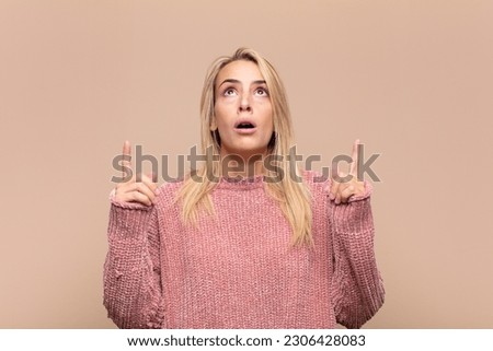  looking shocked, amazed and open mouthed, pointing upwards with both hands to copy space