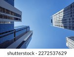 Looking up at skyscapers from the street. The sky is clear and blue. The buildings are a mix of grey and blue. 