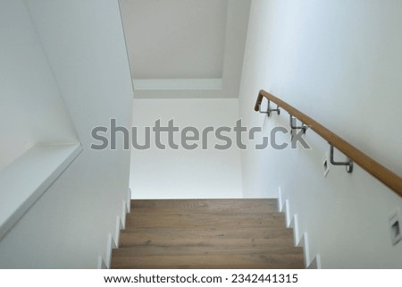 looking up a staircase with wood handrail and stainless steel brackets