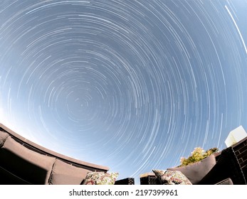 Looking At Star Trails Centered Around The North Star From A City Rooftop