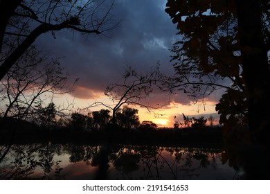 Looking At The Sunset Reflected On The Cloudy Lake Shore