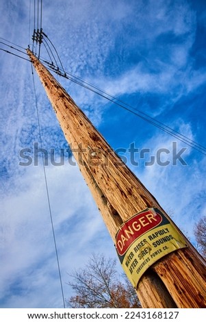 Looking up at telephone pole with large DANGER sign posted about flooding area