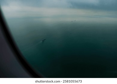 Looking through airplane window with the view of ocean of Hong Kong water. Ships sailing on the sea. Nature scene.