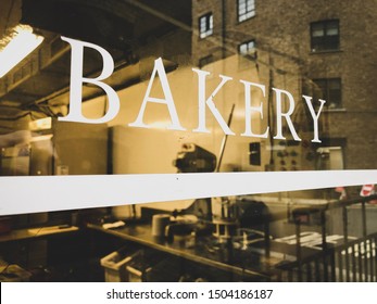 Looking Through A Bakery Window From The Outside. Storefront Sign On The Glass With Reflection Of The City Street.