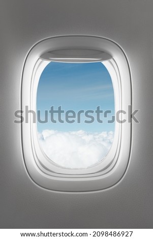 looking through a big jet passenger plane window, above the clouds