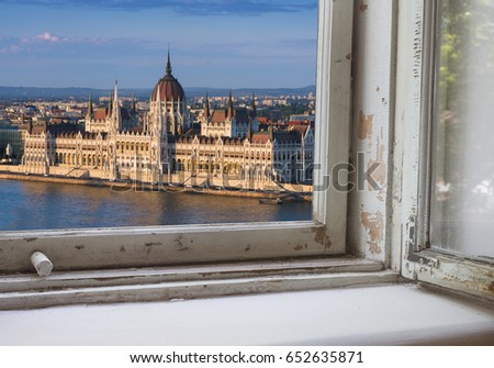 Looking through a castle window, the view of Buda in the foreground with the Hungarian Parliament building on the Pest side of Budapest in the background.