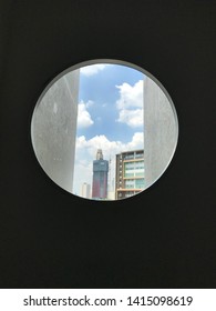 Looking through the circular window, seeing a tall building