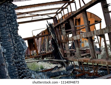 Looking through an old burned, overturned and destroyed train wagon some others rusty wagons, at the old railway at Peloponnese