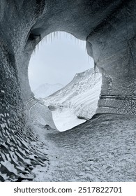 Looking through an opening of an ice cave out into the expanse of nature.