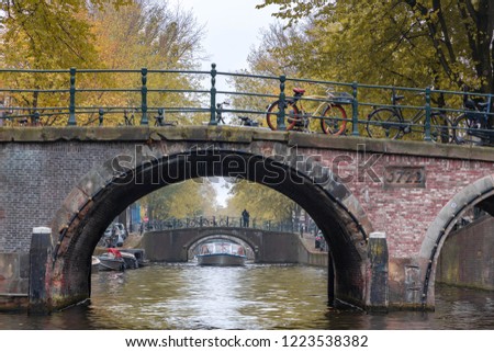 Looking through under canal bridge and cruise boat, View of architecture features traditional houses along Herengracht, Amsterdam, Netherlands.