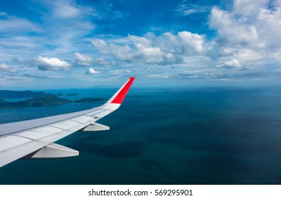 Looking through window aircraft during flight in wing with nice clouds, sky and sea below