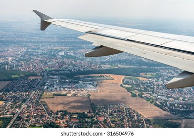 Looking through window airplane on a wing and city of Prague