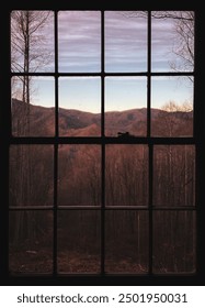 Looking through the window of a cabin at a view of mountains in autumn