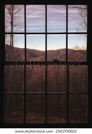 Looking through the window of a cabin at a view of mountains in autumn