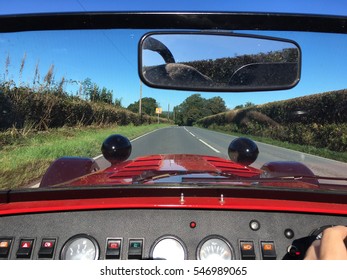 Looking through windscreen on a low red sports car with buttons on the dashboard