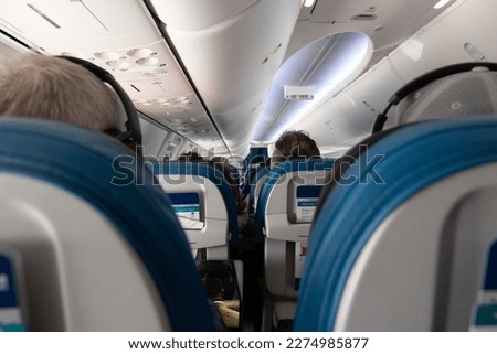 Looking toward the inside front of a passenger jet in between rows of seats