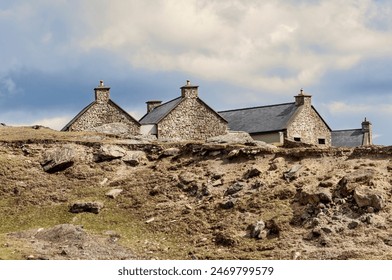 Looking upwards at a cliff face with houses ontop made of stone on Achill Island - Powered by Shutterstock