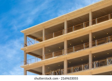 Looking up at the wooden balconies, the vertical supports and interior ceilings of a engineered timber multi story green, sustainable residential high rise apartment building construction project - Shutterstock ID 2169633055