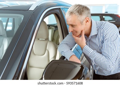 Looks Comfortable. Male Customer Choosing A Car At The Dealership Looking Inside The Automobile Examining Interior Design Of A Car Buying A Car Purchasing Consumer Client Shopper Lifestyle Thoughtful