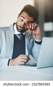 Looks Like Hes Already Lost His Energy And Motivation. Shot Of A Young Businessman Looking Exhausted While Working On A Laptop In An Office.