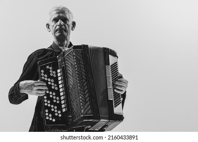 Looks serious, calm. Monochrome portrait of seniot man, retro musician playing the accordion isolated on white background. Concept of art, music, style, older generation, vintage