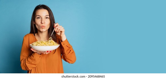 Looks very tasty. Beautiful young girl eating delicious Italian pasta isolated on blue studio background. Holidays, traditions, food, popularity, cafe, love. Healthy carbohydrates. Copy space for ad - Shutterstock ID 2095468465
