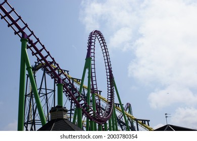 a loop de loop on a roller Coaster with blue sky's and clouds behind it