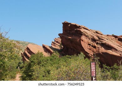 The Loop Trail sign in front of a large red sandstone formation on the Trading Post Trail, Red Rocks Park, Colorado, USA