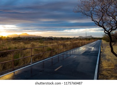 The Loop In Tucson, Arizona. A Walking, Running And Biking Path. A Beautiful Sunset With Wet Pavement Picking Up The Light And Reflecting It. The Railing Disappears In The Distance, Nice Lines. 2018