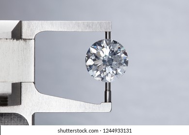 loose big brilliant round diamond is being measure by mm gauge and weight estimator for size
