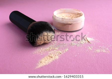 
Loose compact mineral powder for face and fair skin shade ivory porcelain and a large brush for powder and visage on a pink background