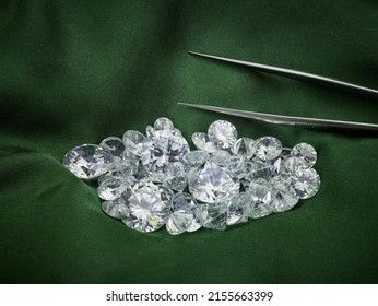 Diamantes sueltos en fondo de seda verde. Fotografía ética temática del diamante con pinzas para clasificar diamantes. 