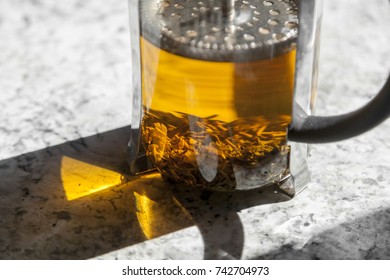 Loose leaf tea steeps in a french press on a white marble counter top.  - Powered by Shutterstock