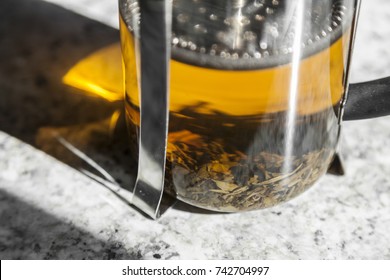 Loose leaf tea steeps in a french press on a white marble counter top.  - Powered by Shutterstock