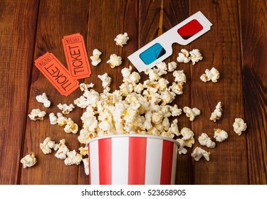 Loose popcorn in striped box, two tickets to the cinema and 3D glasses on a wooden background - Powered by Shutterstock