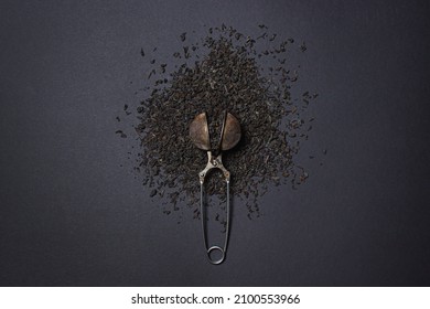 Loose Tea On A Black Background. Loose Tea In An Old Brewing Sieve. The Concept Of Loose Tea And Tea Drinks.