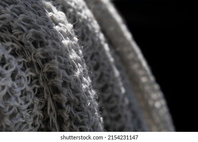 Loose-knit pure wool shawls hang outside in the daylight on black background. Focus on the sunlit edge in the left part of the photo