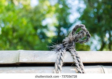 Loosen And Old Rope Tied On Bamboo Wood In Green Natural Bokeh Background.