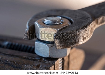 Loosening the nut using a wrench and a vise. Using old spanner wrench and clamp to remove nut from bolt, close up