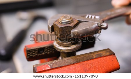 Loosening rusty nut using an adjustable crescent wrench and vise. Using spanner wrench and clamp to remove nut from bolt.