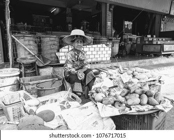 Lopburi, Thailand - April 21, 2018: Elderly woman sells mangoes at a local outdoor market.