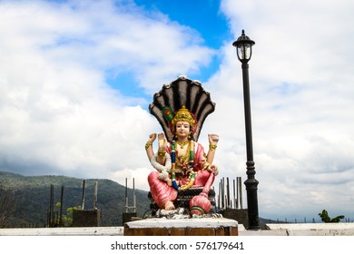 Lord Vishnu Statue In A Sitting Position On Blue Sky Background.