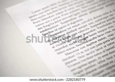 Lorem Ipsum dolor text on printed on paper in black and white, sample of document, side view, selective focus
