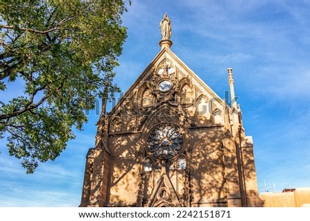 The Loretto Chapel historic old church in Santa Fe, New Mexico in United States with closeup of exterior facade and tree shadow on sunny day against blue sky with nobody