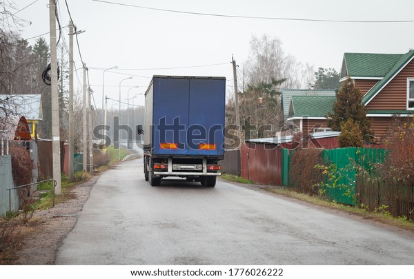 Lorry goes on\
empty rural road at day, rear\
view
