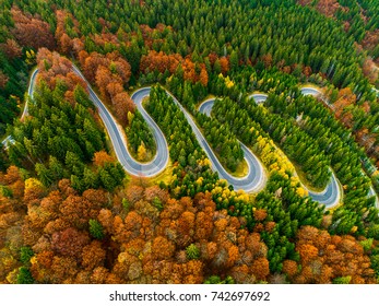 Lorry Winding Up Its Way On A Curvy Road Through Autumn Colored Forest