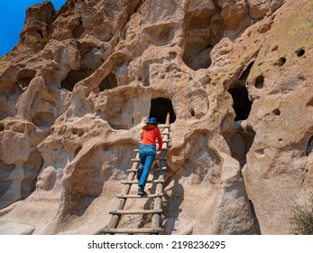 Los Alamos, New Mexico, USA - April 30, 2022:    Woman Climbing A Ladder At Talus House, Cliff Dwellings, Bandelier National Monument.