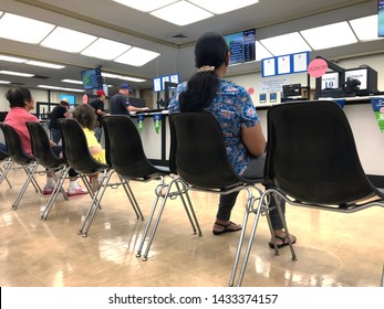 LOS ANGELES, April 25, 2019: DMV Department of Motor Vehicles Culver City interior. A Latino woman sits on a chair, waiting her turn, near the counter inside the waiting room.