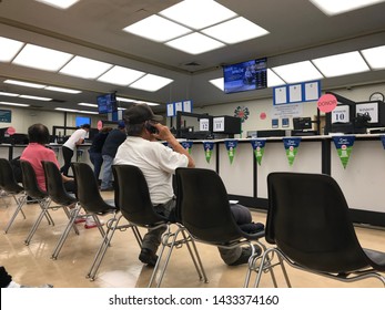 LOS ANGELES, April 25, 2019: DMV Department of Motor Vehicles Culver City interior. Latino man talking on his cell phone while sitting on a chair, waiting his turn, near the counter inside the DMV