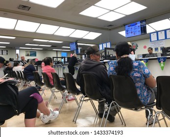 LOS ANGELES, April 25, 2019: DMV Department Of Motor Vehicles Culver City Interior. A Latino Couple Sit On Chairs, Waiting Their Turn, Near The Counter Inside The DMV Waiting Room.